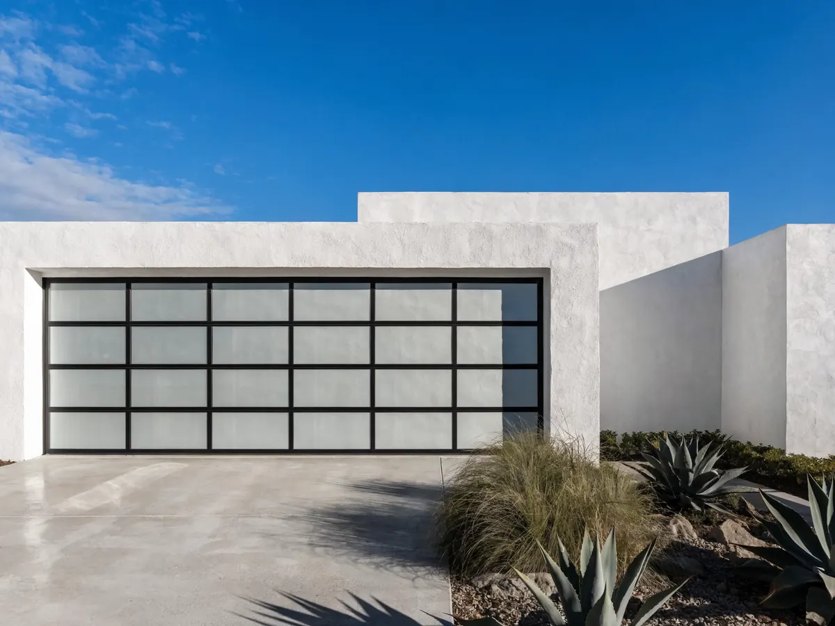 Full view garage door with a black anodised aluminium frame and sixteen frosted glass panels, closed on a modern flat roofed white stucco Florida house