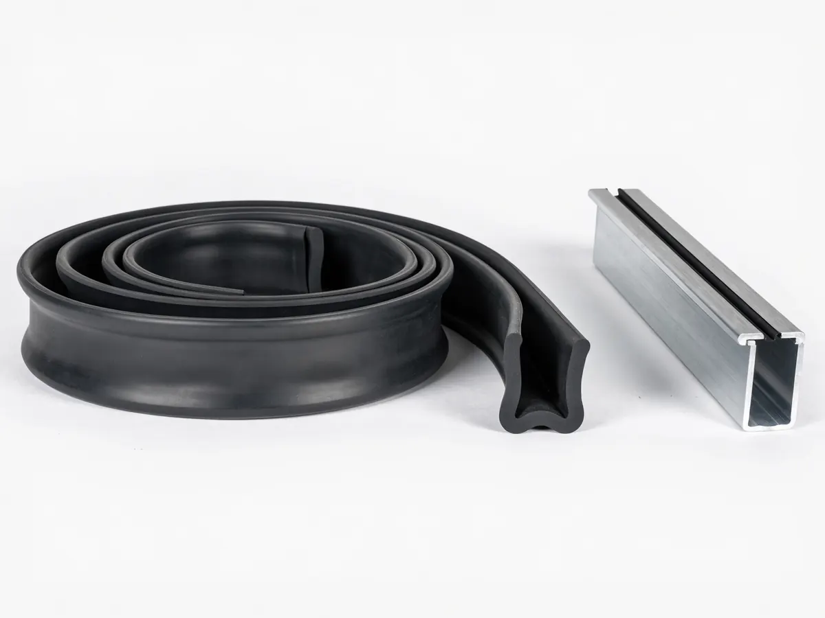 Black rubber U shaped garage door bottom seal, partly coiled, beside the aluminium retainer track it slides into