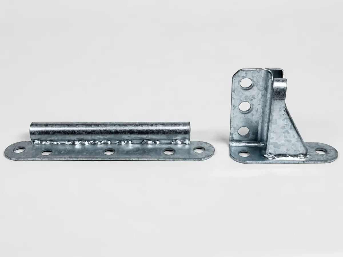 Two galvanised steel garage door hinges lying flat, a flat leaf section hinge with a roller carrier tube and a taller end hinge bracket